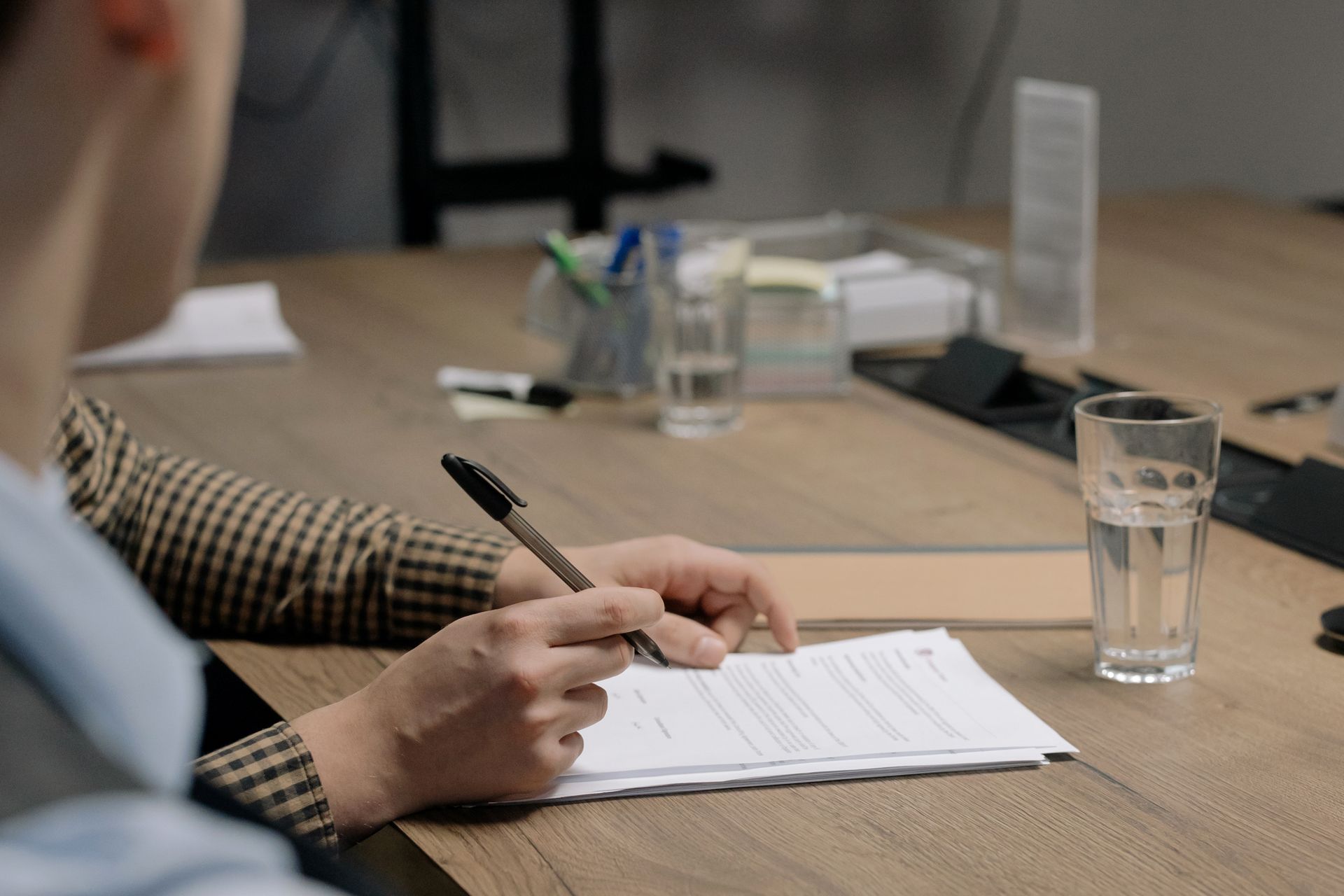 Persona firmando documentos en una mesa de madera